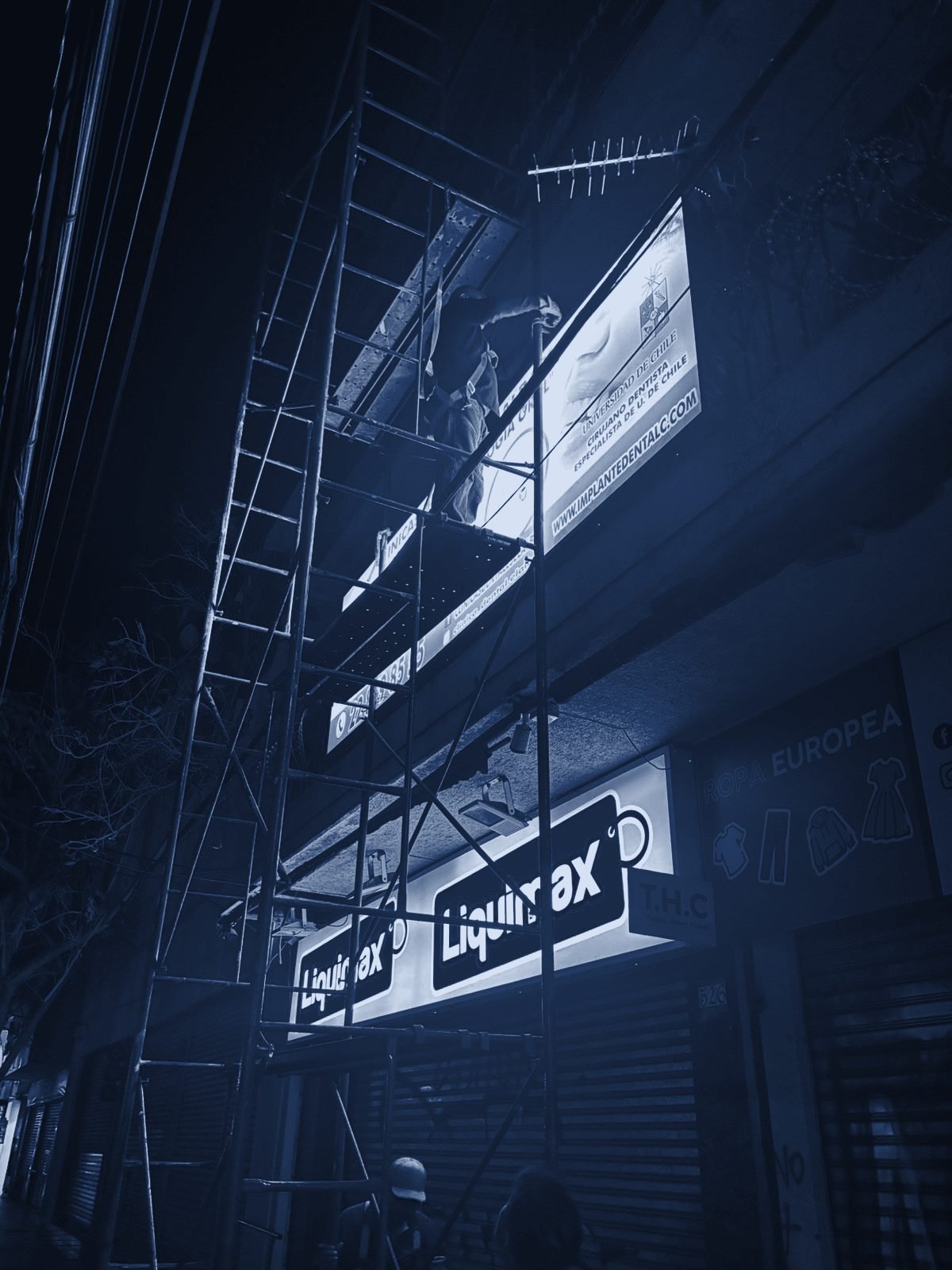 Instalación nocturna de letreros en la fachada de un local
