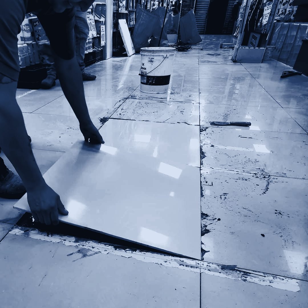 Técnico instalando palmetas de porcelanato en una sala de ventas